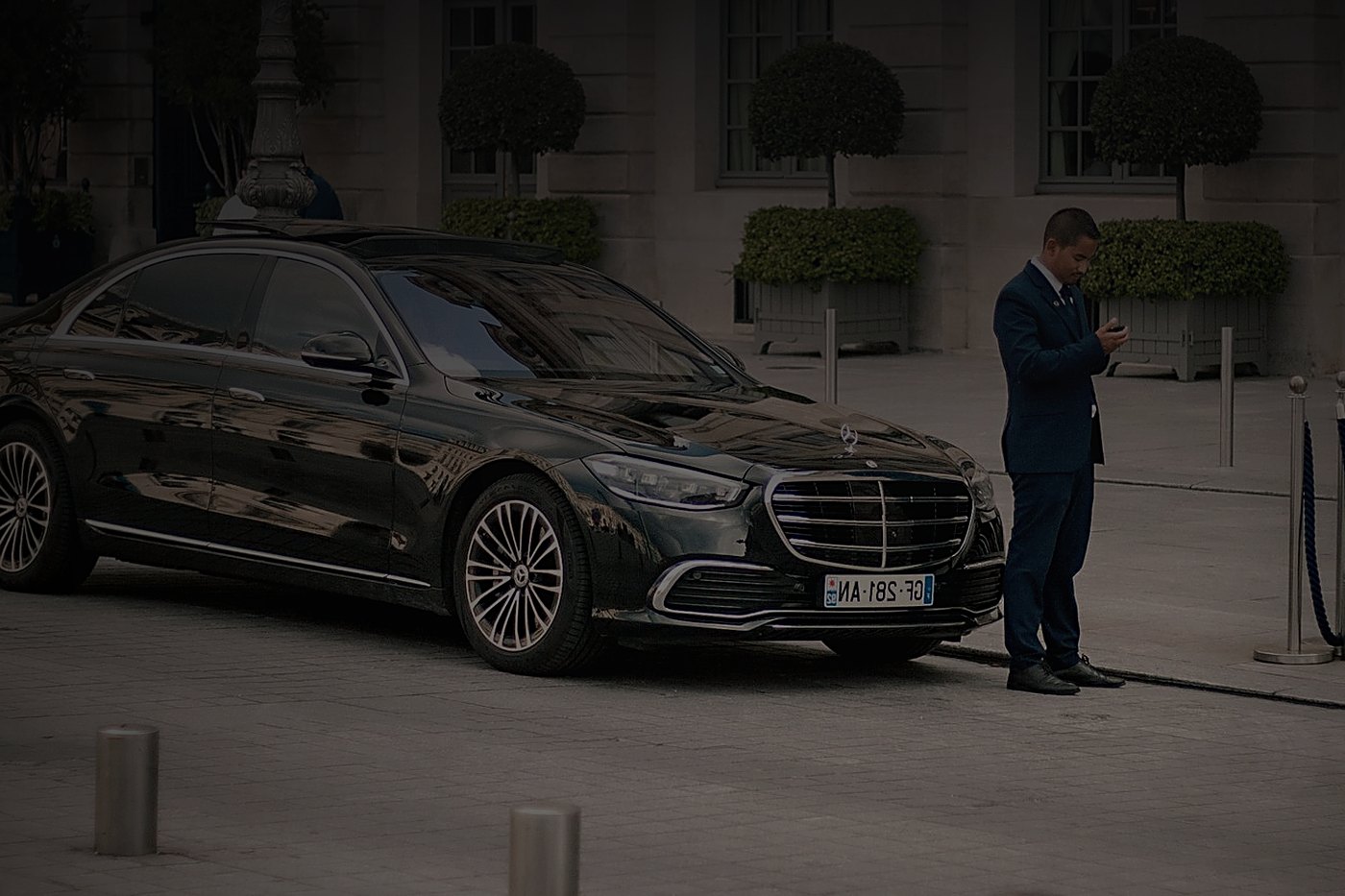 Professional chauffeur beside a black Mercedes-Benz S-Class
